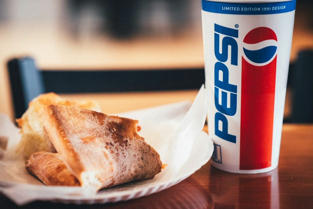 a piece of bread and a cup of pepsi on a table