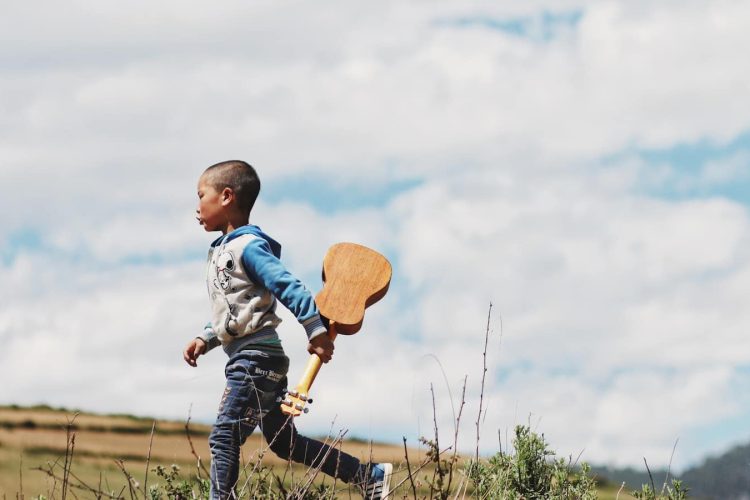 boy running while holding ukelele