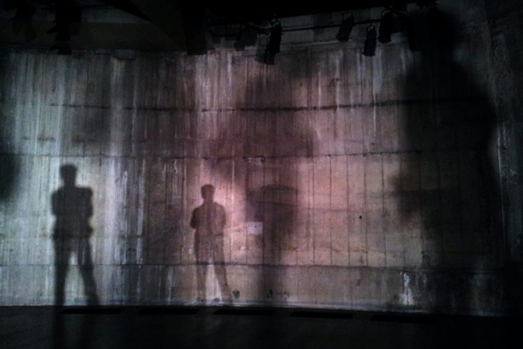 silhouette of man standing near wall on dark area