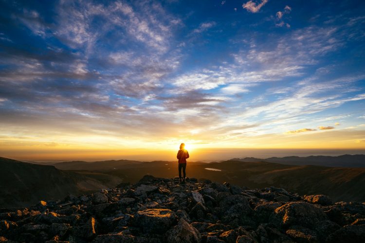 person standing on rocky mountain under blue sky during daytime