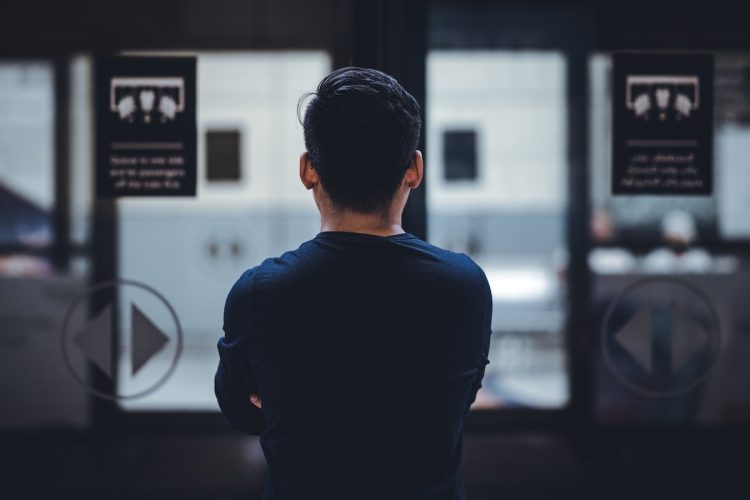man wearing blue top facing glass door