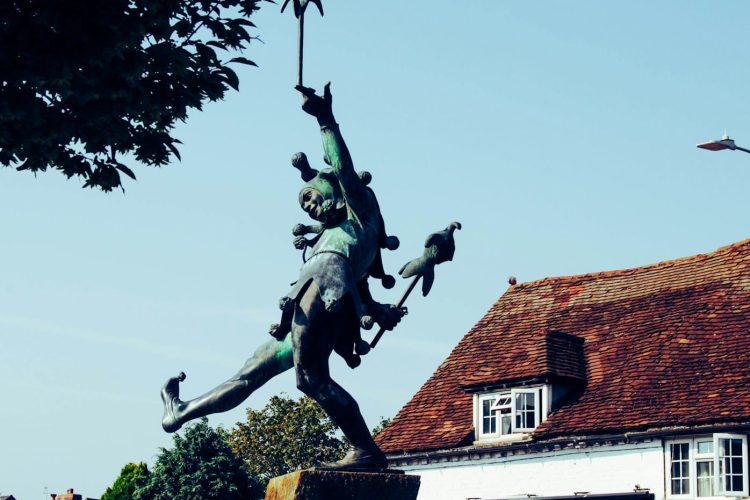woman with birds statue near house during daytime
