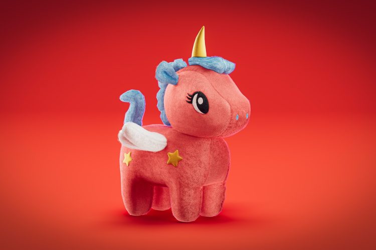 a pink stuffed animal with a gold horn on its head