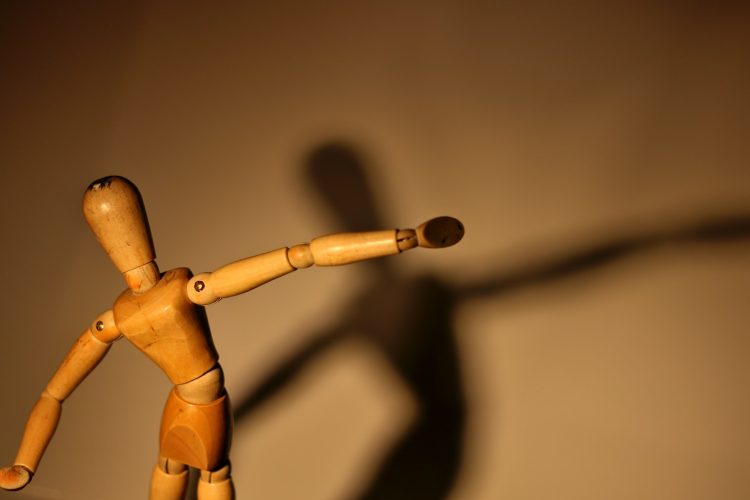 a wooden toy with a long shadow on a wall