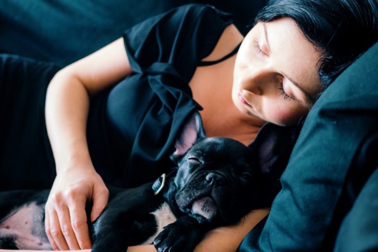 woman and black French bulldog sleeping on sofa