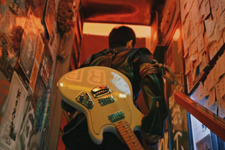 man in black jacket playing white electric guitar