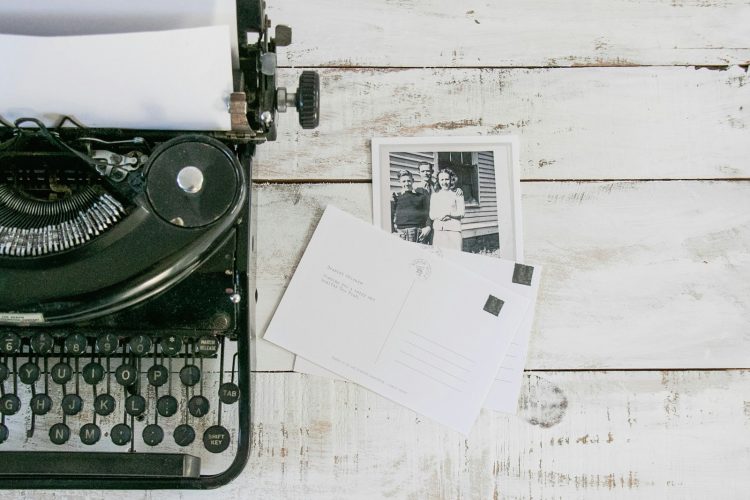 black typewriter beside white printer paper