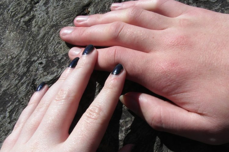 two hands holding each other on a rock