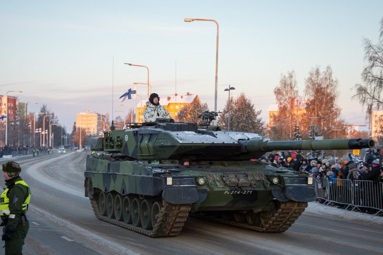 a military tank driving down a street next to a crowd of people